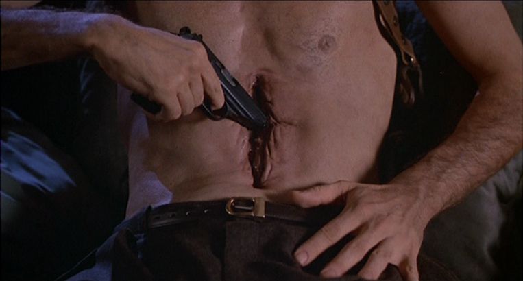 James Woods mette una pistola nella fessura vaginale del suo stomaco in Videodrome