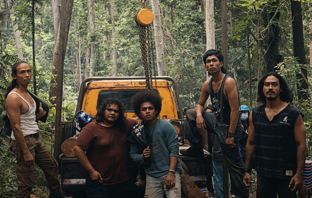Cinque persone in piedi dietro un camion con pianale nella giungla.