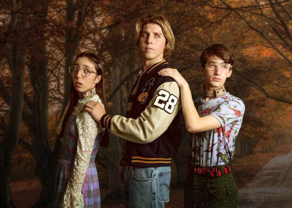Tre adolescenti, due con collari elettronici marroni al collo, in posa per un ritratto di famiglia a Wyrm.