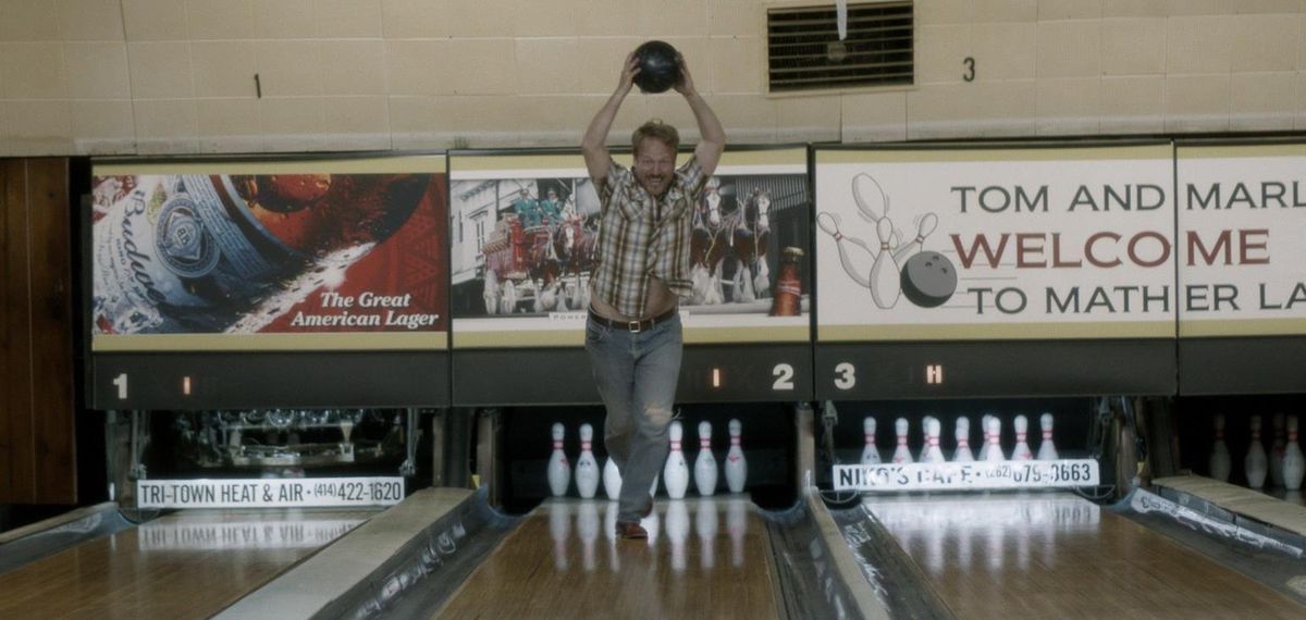Wayne Stobierski (David Sullivan) corre lungo una pista da bowling tenendo una palla da bowling sopra la sua testa.