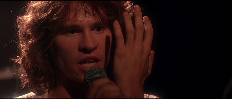 Val Kilmer nel ruolo di Jim Morrison, esibendosi in The Doors.