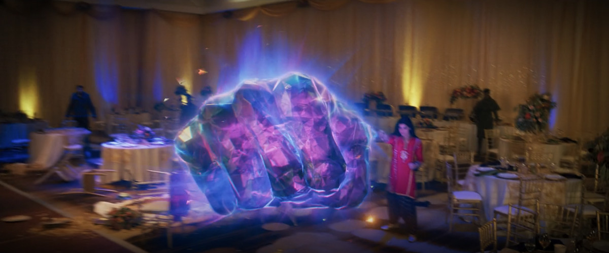 Kamala Khan/la signora  La Marvel lancia un grande pugno elastico fatto di luce dura sfaccettata, all'interno di una stanza decorata per un matrimonio in Ms. Marvel. 