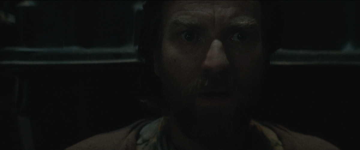 Ewan McGregor nei panni di Obi-Wan Kenobi reagisce con un orrore silenzioso quando scopre dopo dieci anni che Anakin Skywalker è ancora vivo in Obi-Wan Kenobi (2022). 