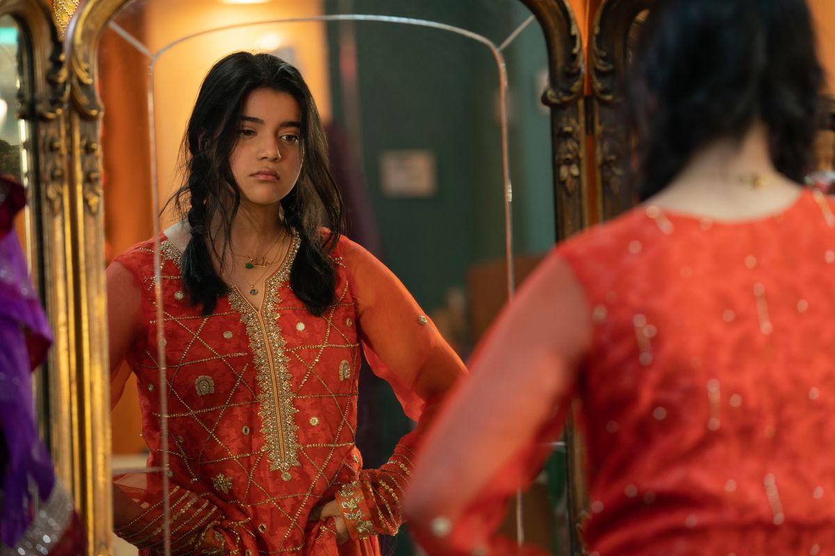 kamala in un abito tradizionale pakistano arancione, guardandosi allo specchio