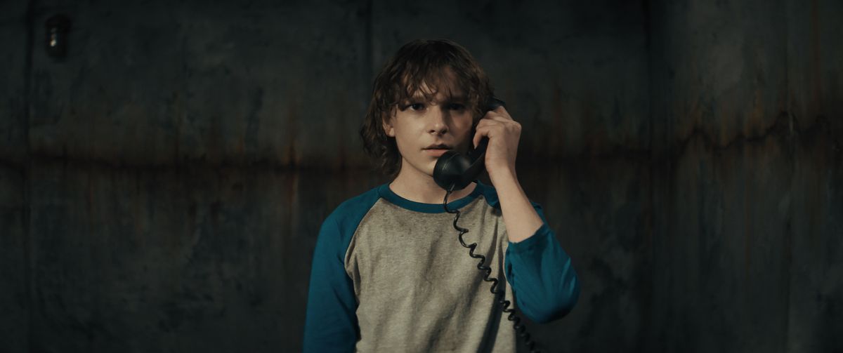 La vittima del bambino Finney Shaw (Mason Thames) è sola in una stanza buia, con in mano un telefono nero, in The Black Phone.
