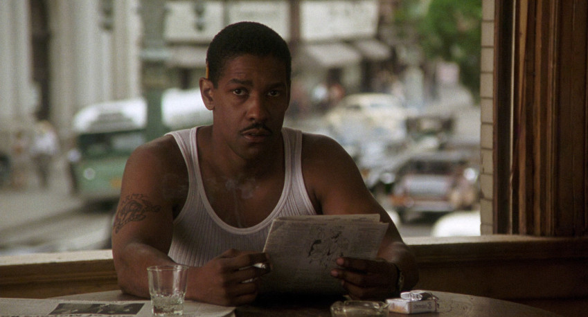 Denzel Washington, con indosso una canotta bianca, legge il giornale in Devil in a Blue Dress.