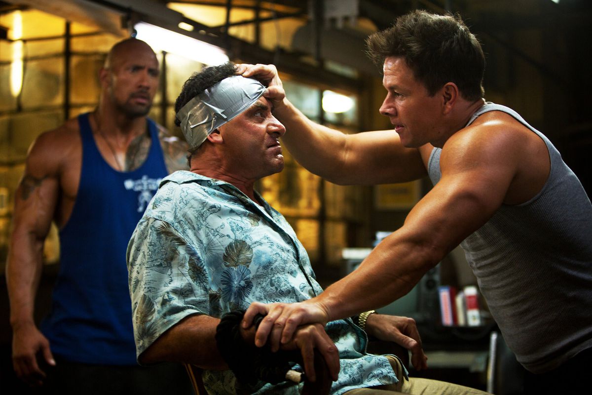 Mark Wahlberg e Dwayne Johnson osservano un Tony Shalhoub rapito in Pain & Gain.