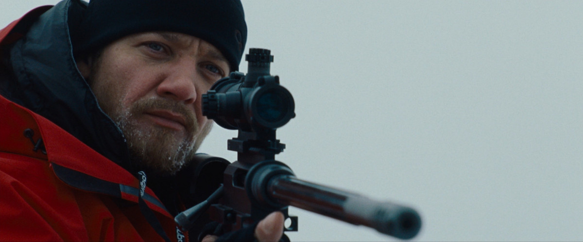 Jeremy Renner, vestito con abbigliamento invernale, impugna un fucile in The Bourne Legacy