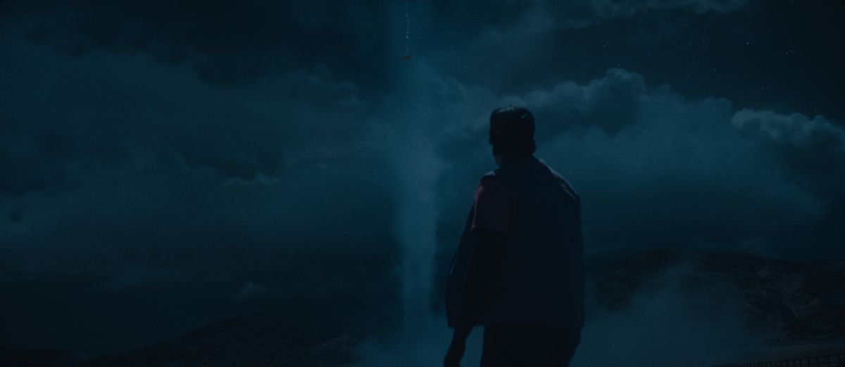 OJ (Daniel Kaluuya), visto in silhouette da dietro di notte, guardando un UFO nel cielo in Nope
