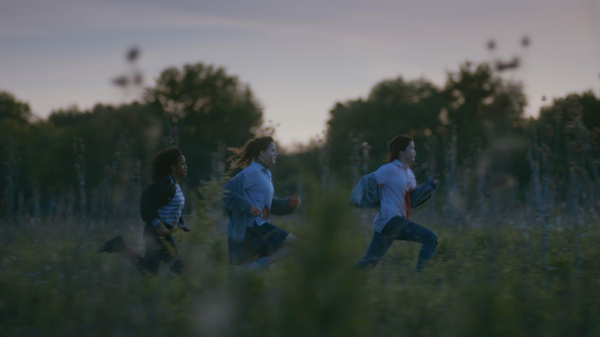 Tre delle ragazze di carta che corrono in un campo