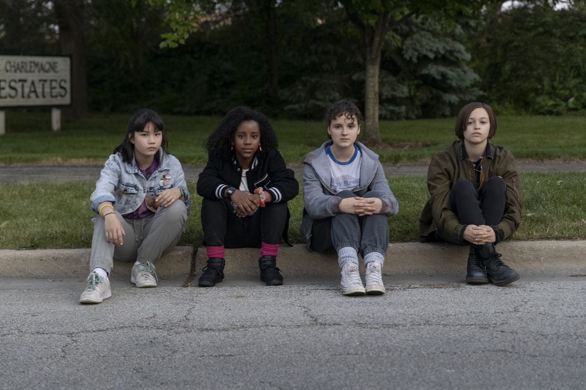 Le quattro ragazze di carta sedute su un marciapiede