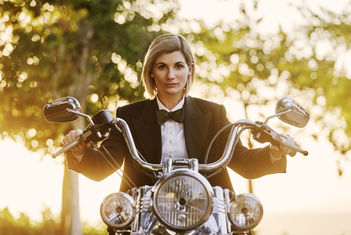 Jodie Whittaker nei panni del Dottore nella dodicesima stagione del rianimato Doctor Who, in sella a una moto d'epoca e indossa un blazer e un papillon.
