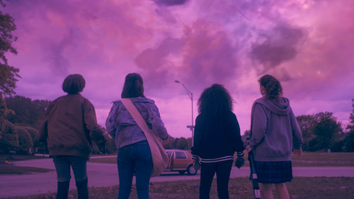 Le quattro ragazze di carta in piedi e di fronte alla telecamera verso il cielo rosa brillante