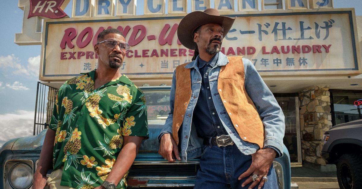 Jamie Foxx (con una camicia hawaiana) e Snoop Dogg (con cappello da cowboy e gilet) si appoggiano a un camion in Day Shift