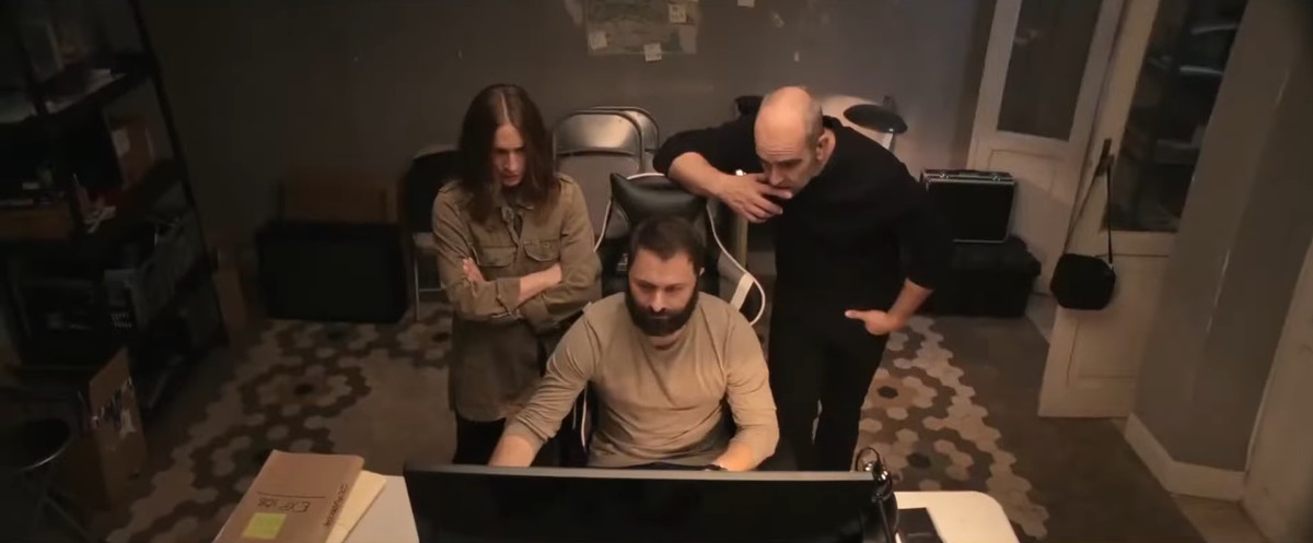 Tre persone stanno attorno a un computer in Code Name: Emperor.