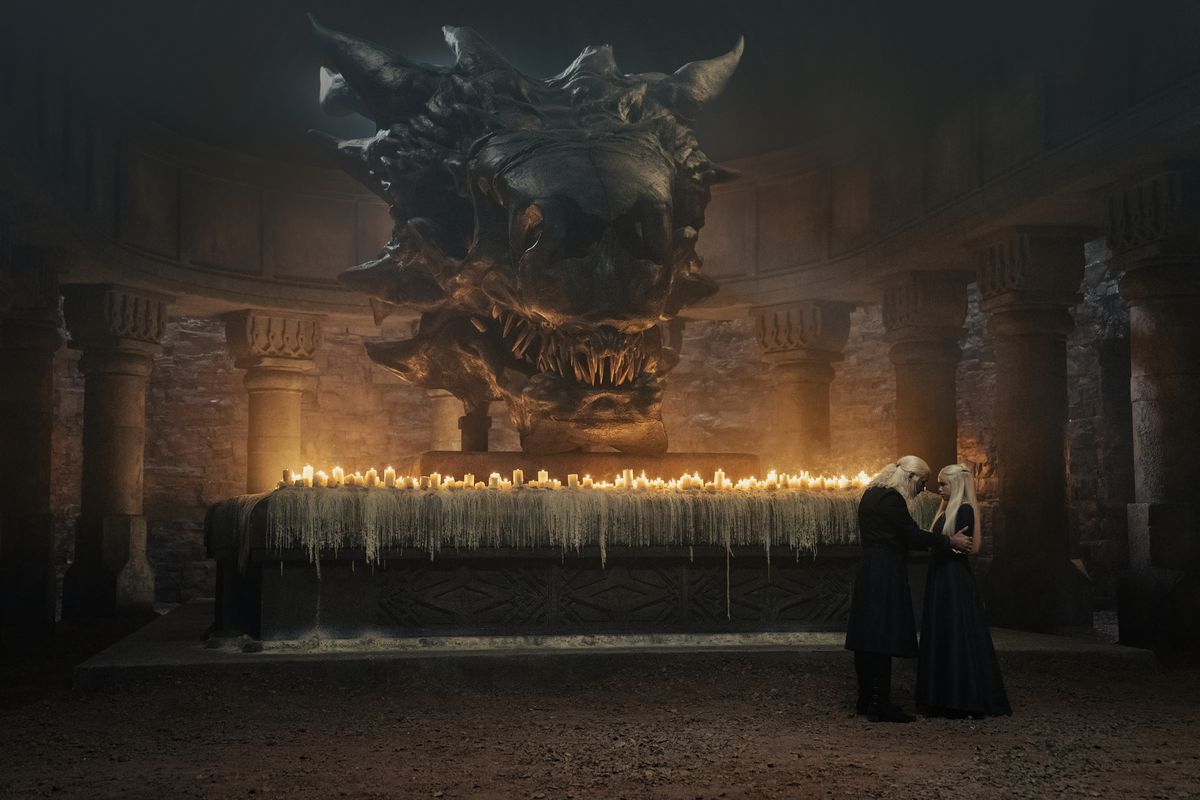 Viserys parla con sua figlia davanti a un altare con un mazzo di candele e un teschio di drago gigante in House of the Dragon