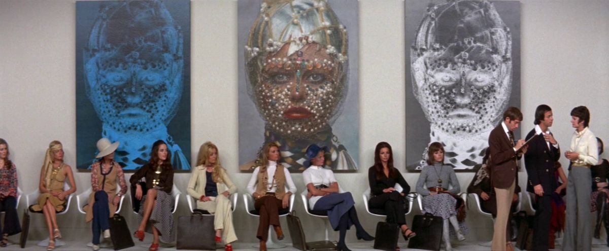 Un gruppo di donne, tra cui Jane Fonda, siede in fila davanti a tre dipinti.