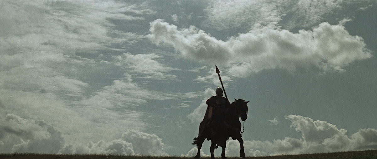 Una suggestiva immagine di un cavaliere con in mano una lancia, che si staglia contro un vasto cielo azzurro tempestato di nuvole