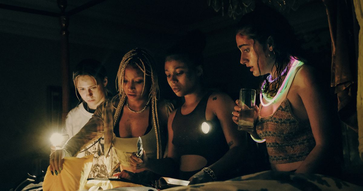 Quattro delle donne di Bodies Bodies Bodies si raccolgono nell'oscurità attorno a una candela