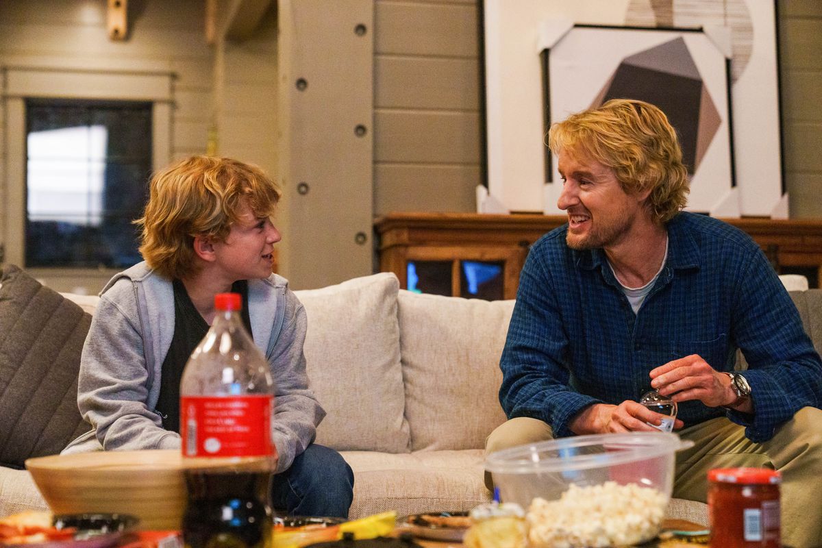 Charlie, un ragazzino, siede con suo padre, Jack, su un divano con popcorn e bibite davanti a loro