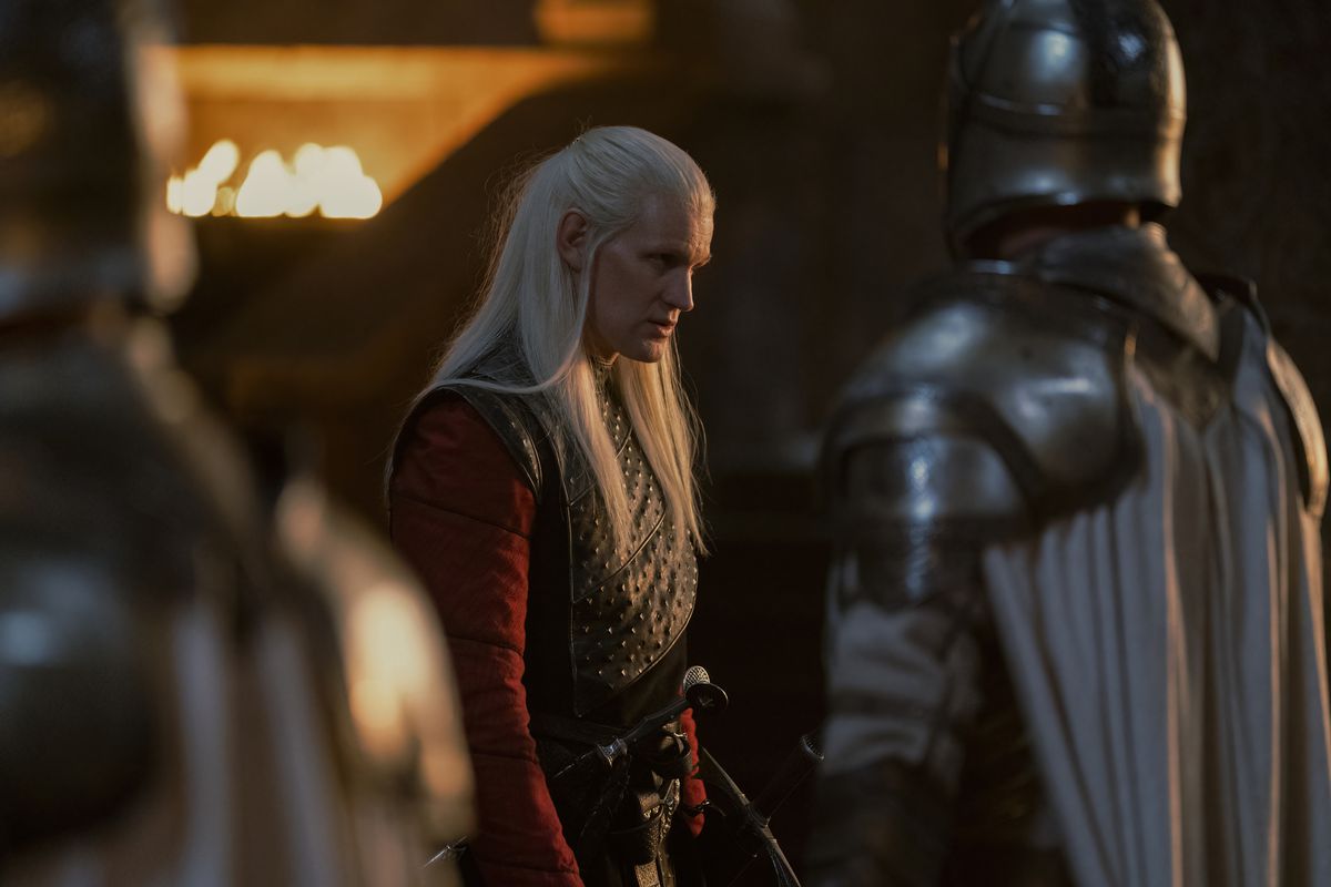 Matt Smith nei panni di Daemon Targaryen in piedi e dall'aspetto feroce con le guardie di fronte a lui