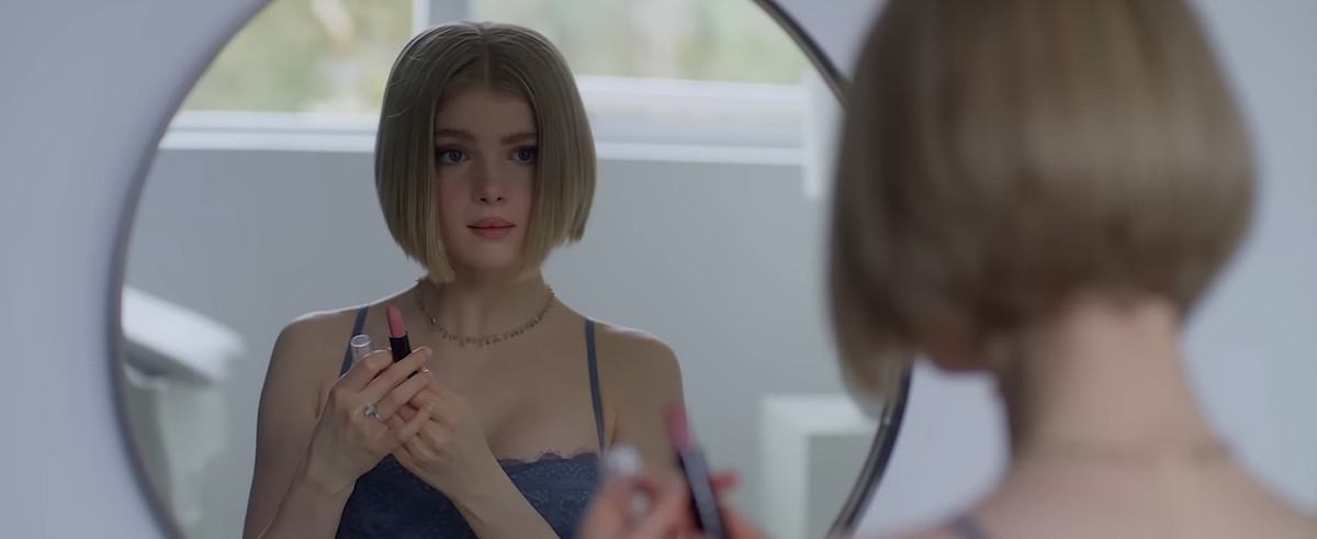 Meredith (Elena Kampouris) si esamina allo specchio mentre tiene in mano il rossetto in Wifelike