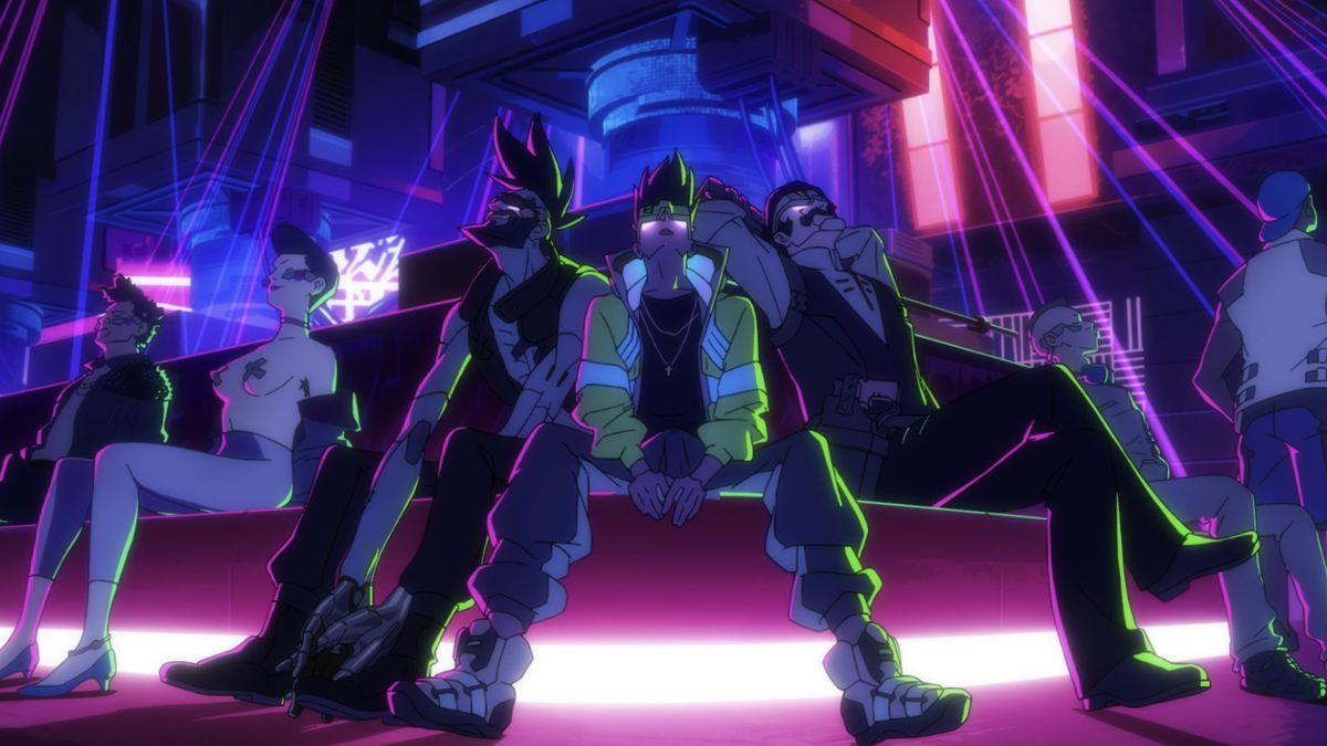 Tre personaggi seduti su una panchina di un club con luci laser che si illuminano di rosa, blu e viola intorno a loro;  stanno tutti guardando in alto, così come le persone vicine