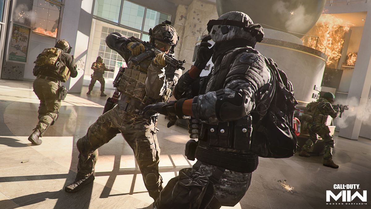 Un giocatore punta un fucile mitragliatore contro un avversario all'interno di un edificio per uffici in fiamme in uno screenshot di Call of Duty: Modern Warfare 2