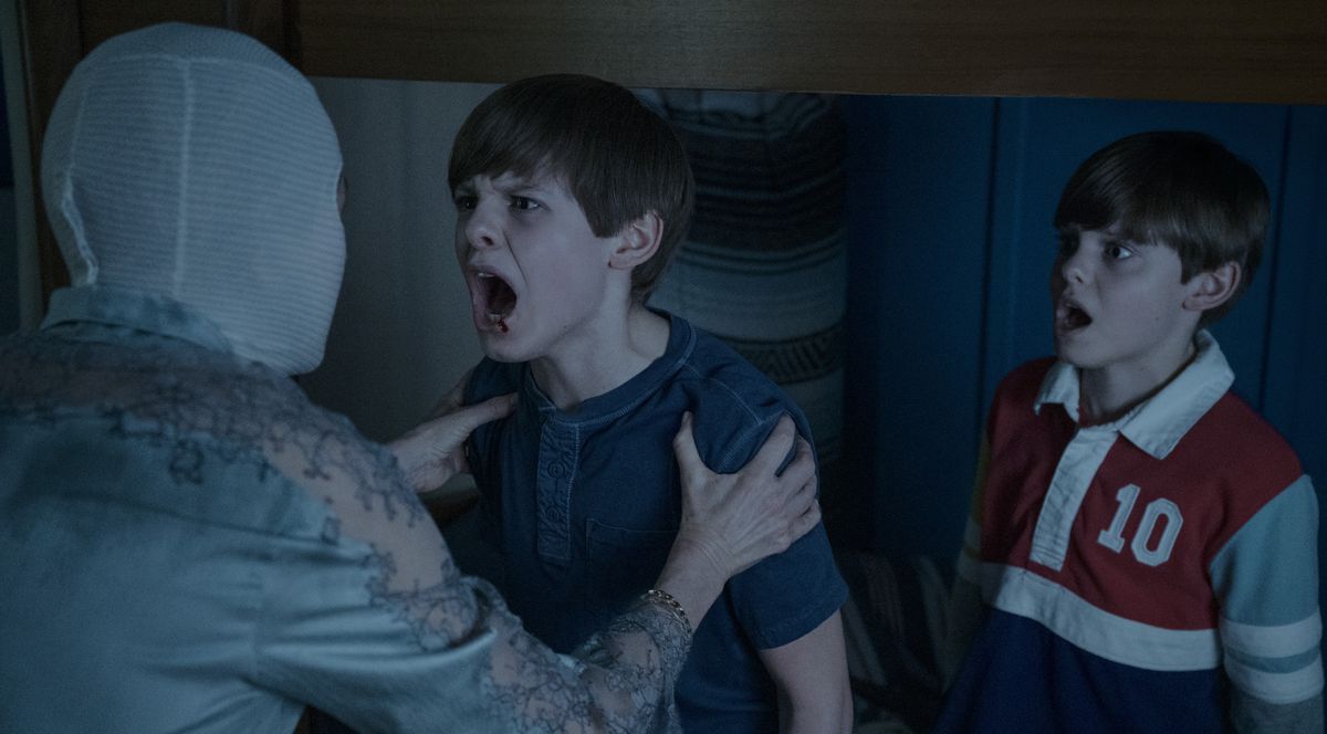 La madre (Naomi Watts) si aggrappa a uno dei suoi gemelli mentre lui le urla in faccia, mentre l'altro guarda sotto shock, nel film Goodnight Mommy del 2022