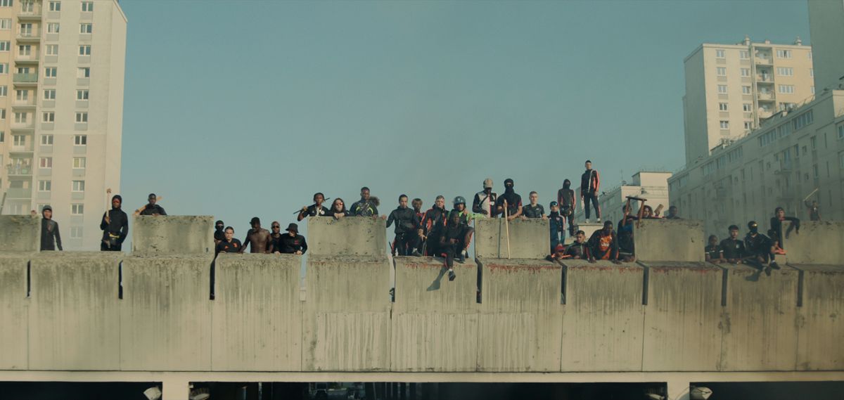 Un folto gruppo di manifestanti si trova in cima a un edificio che guarda in basso ad Athena