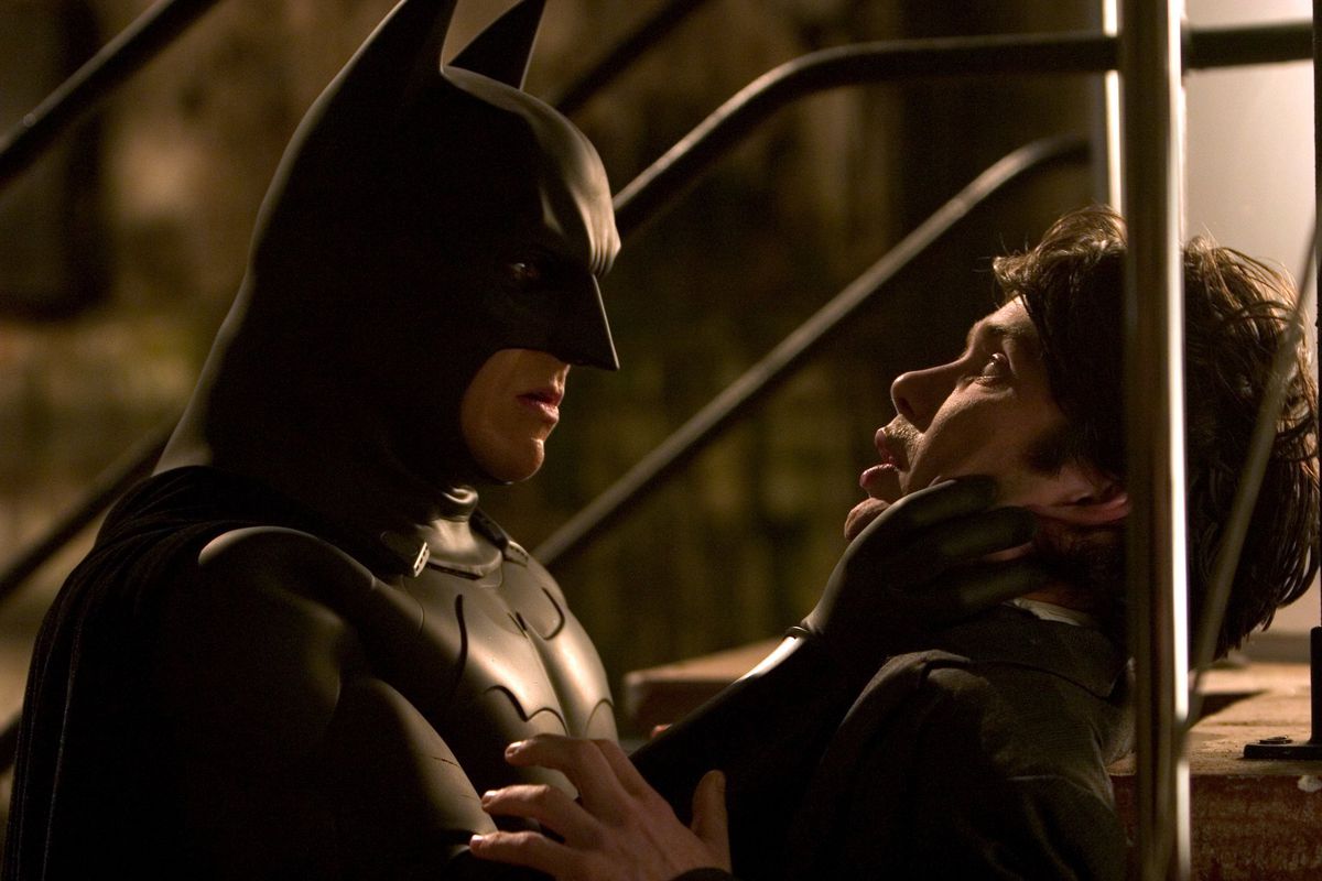 Batman minaccia Jonathan Gru su una scala, con la mano intorno alla gola della gru