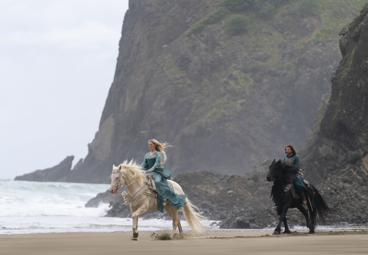 Galadriel cavalca un cavallo bianco con Elendir dietro di lei su un cavallo nero, su una spiaggia