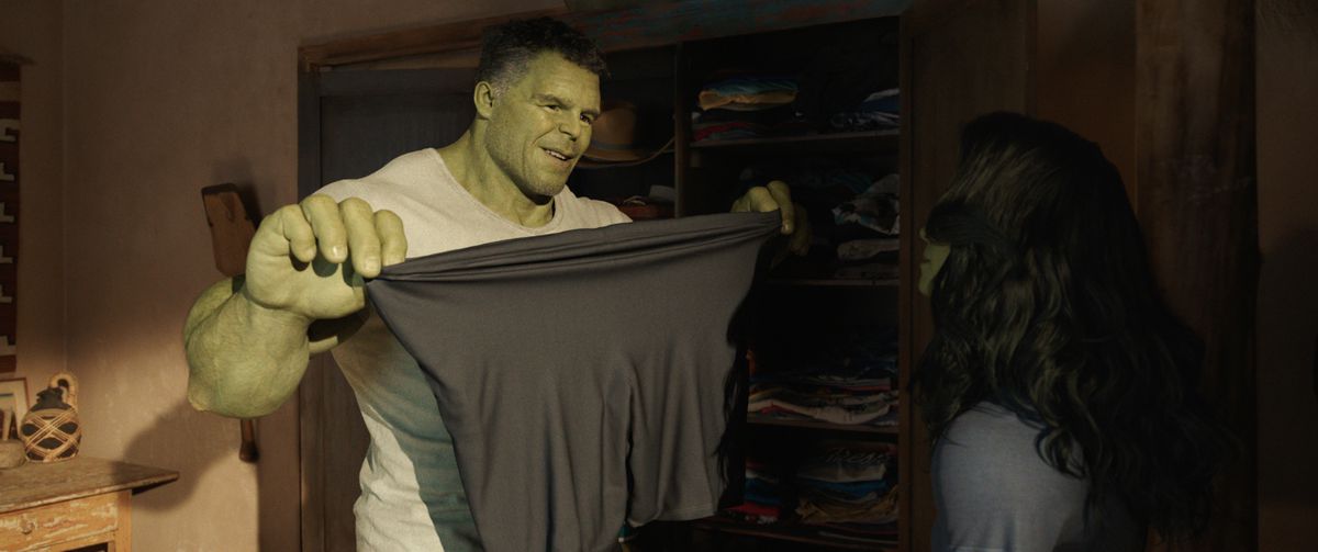 Bruce Banner nei panni di Smart Hulk che tiene in mano pantaloncini di spandex e li allunga di fronte a Jen, che è nel personaggio di She-Hulk
