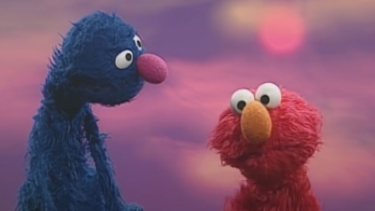 Grover recita e ad Elmo durante una canzone in Sesame Street davanti allo sfondo di un tramonto.