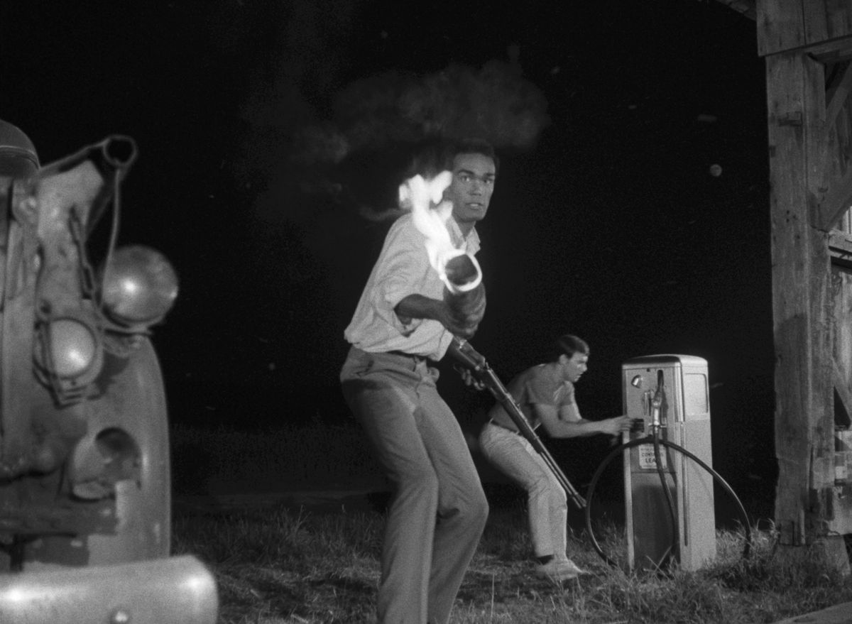 Duane Jones nei panni di Ben brandisce una torcia contro alcuni ghoul in una stazione di servizio in La notte dei morti viventi