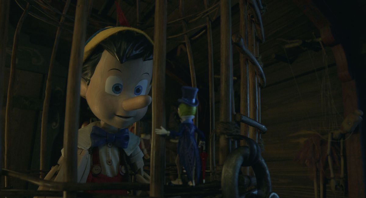 Uno strano Pinocchio in CG con gli occhi spenti fissa Jiminy Cricket da una gabbia nel remake live-action della Disney del classico animato degli anni '40 Pinocchio