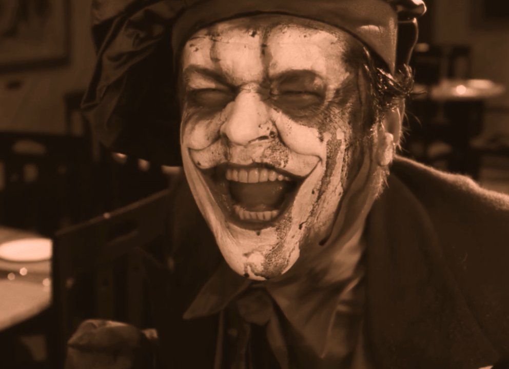 Jack Nicholson nei panni del Joker che ulula dalle risate mentre il suo trucco si stacca per rivelare la sua pelle bianca e candeggina in Batman: The Silent Motion Picture.