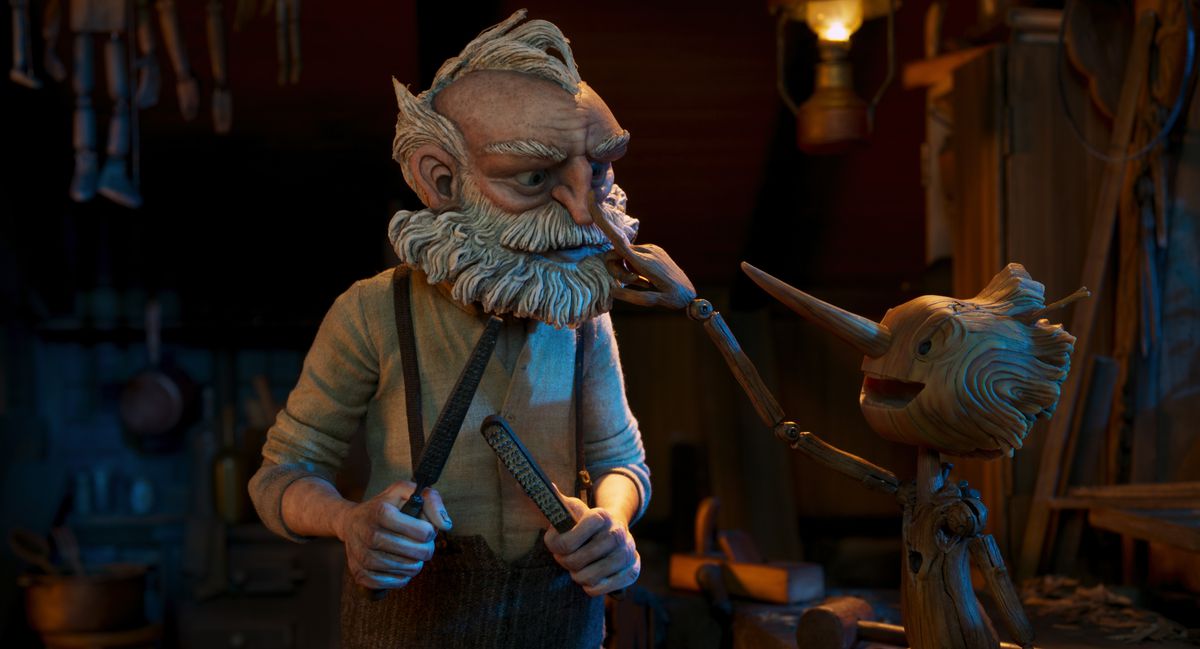 Il ragazzo di legno Pinocchio preme giocosamente il naso di Geppetto.  Geppetto ha in mano degli attrezzi