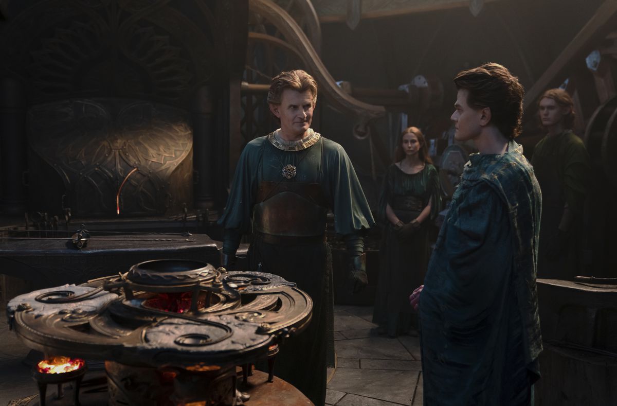 Celebrimbor in piedi alla sua fucina guardando Elrond, con altre persone in piedi dietro di loro