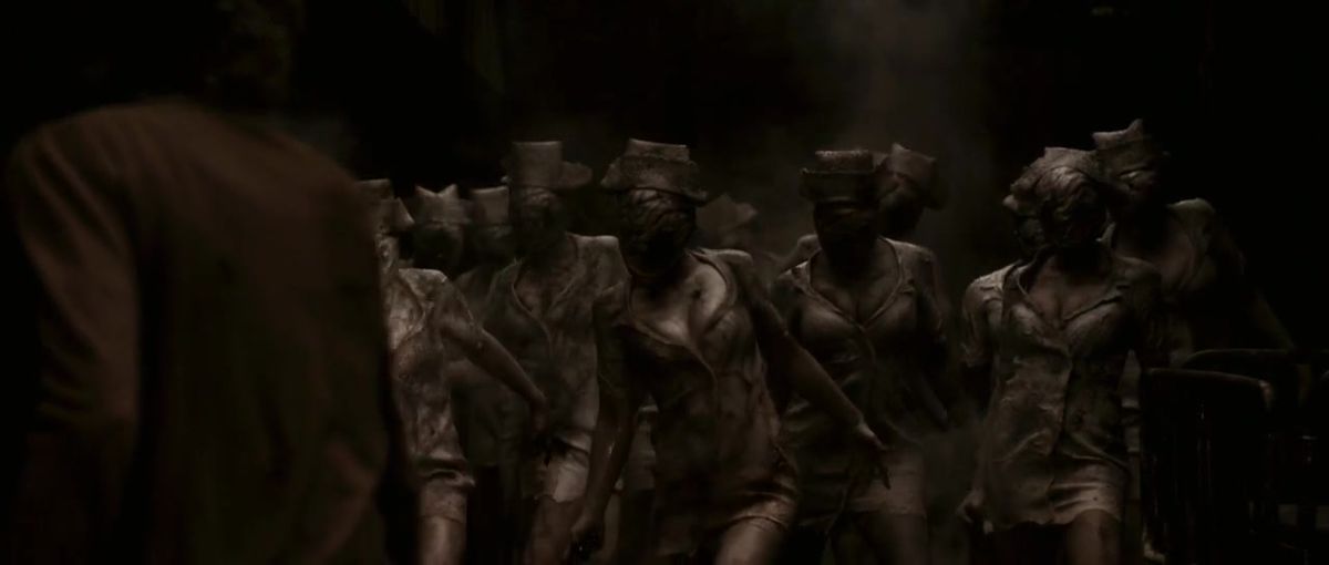Diverse infermiere zombie senza volto stanno di fronte a una donna bionda nel film di Silent Hill