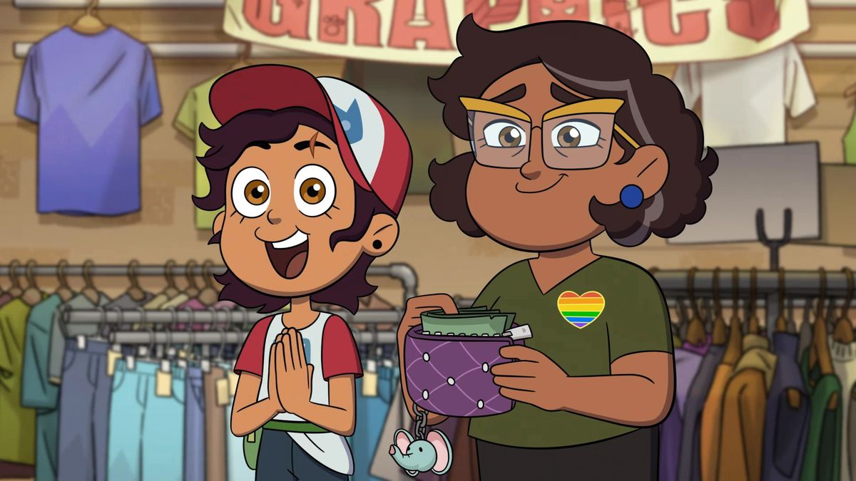 luz e Camila in piedi in un negozio dell'usato;  luz sembra eccitata e Camila indossa un distintivo dell'orgoglio arcobaleno