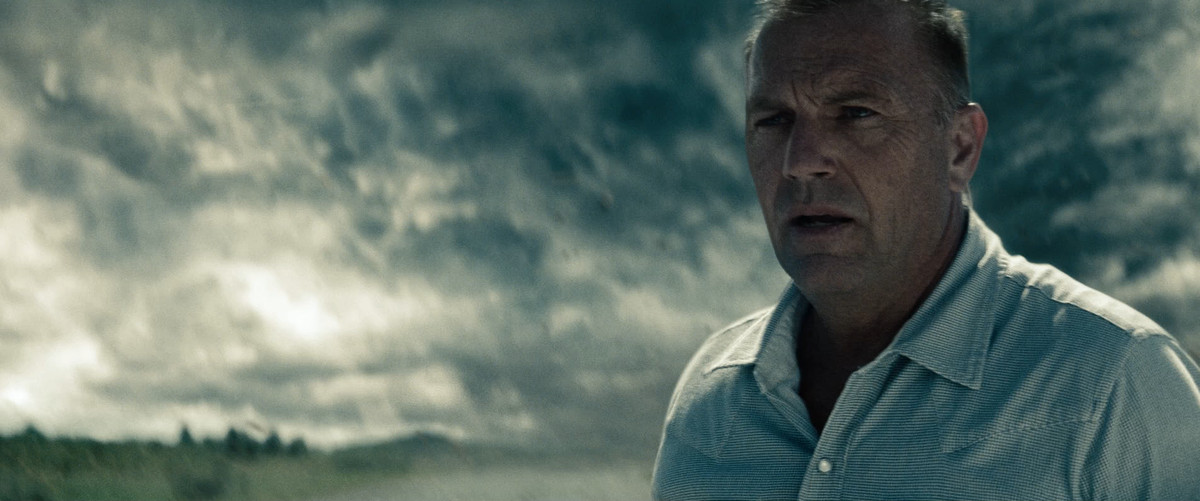 Kevin Costner in Man of Steel, con nuvole tempestose dietro di lui e preoccupazione sul viso.