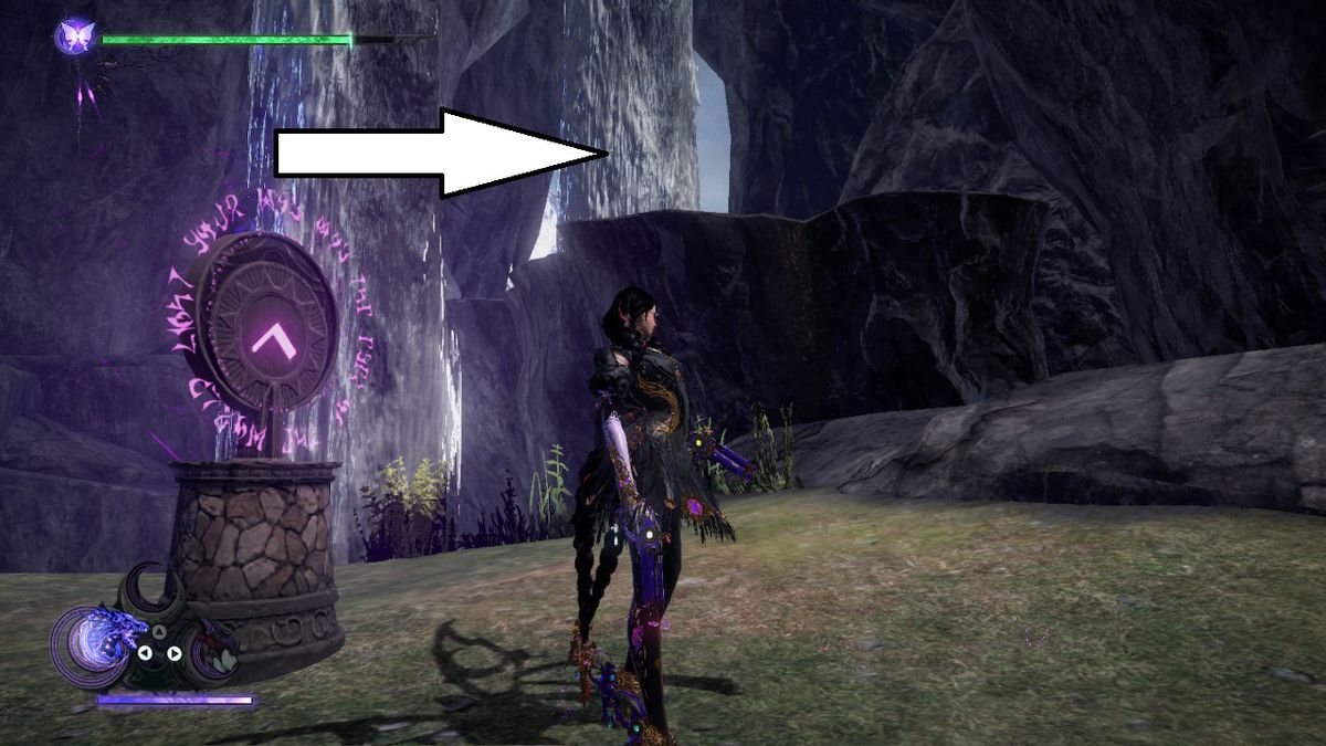 Bayonetta si trova in una grotta dietro una cascata accanto a un ciondolo in Bayonetta 3.