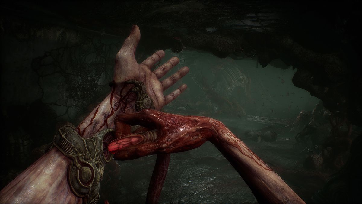 Il personaggio del giocatore in Scorn inserisce un tubo rosso luminoso nel suo polso, con entrambe le mani macchiate di sangue