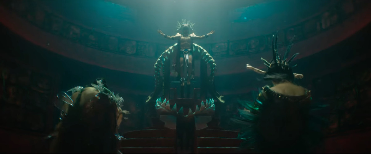 Namor scende nelle profondità della sua sala del trono indossando un'elaborata corona di piume con le braccia tese in Black Panther: Wakanda Forever