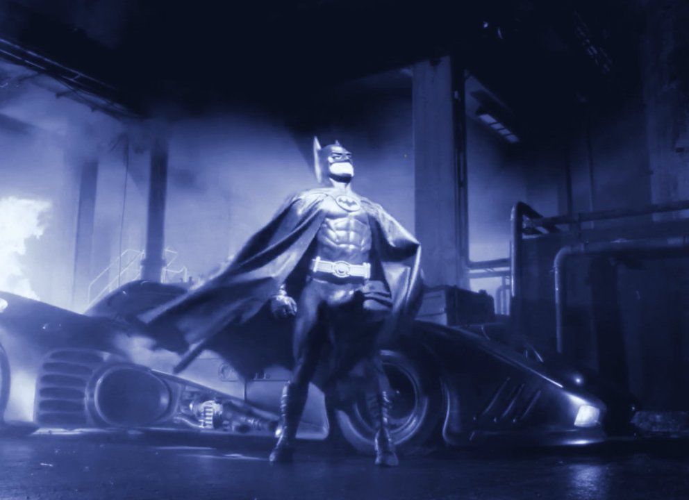 Uno screenshot di Michael Keaton in costume come Batman in Batman di Tim Burton, modificato con una sfumatura di colore blu nello stile dei primi film muti colorati.