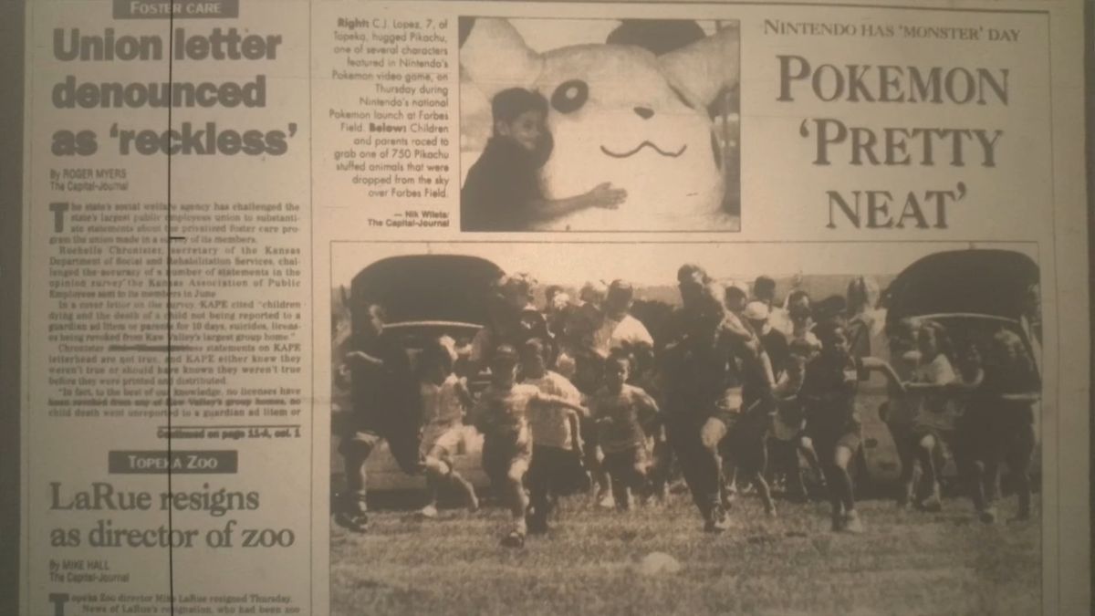 Una vecchia edizione del Topeka Capital Journal, con colorazione seppia.  Una piccola immagine mostra un bambino che abbraccia un peluche gigante di Pikachu.  Il lettore del titolo 