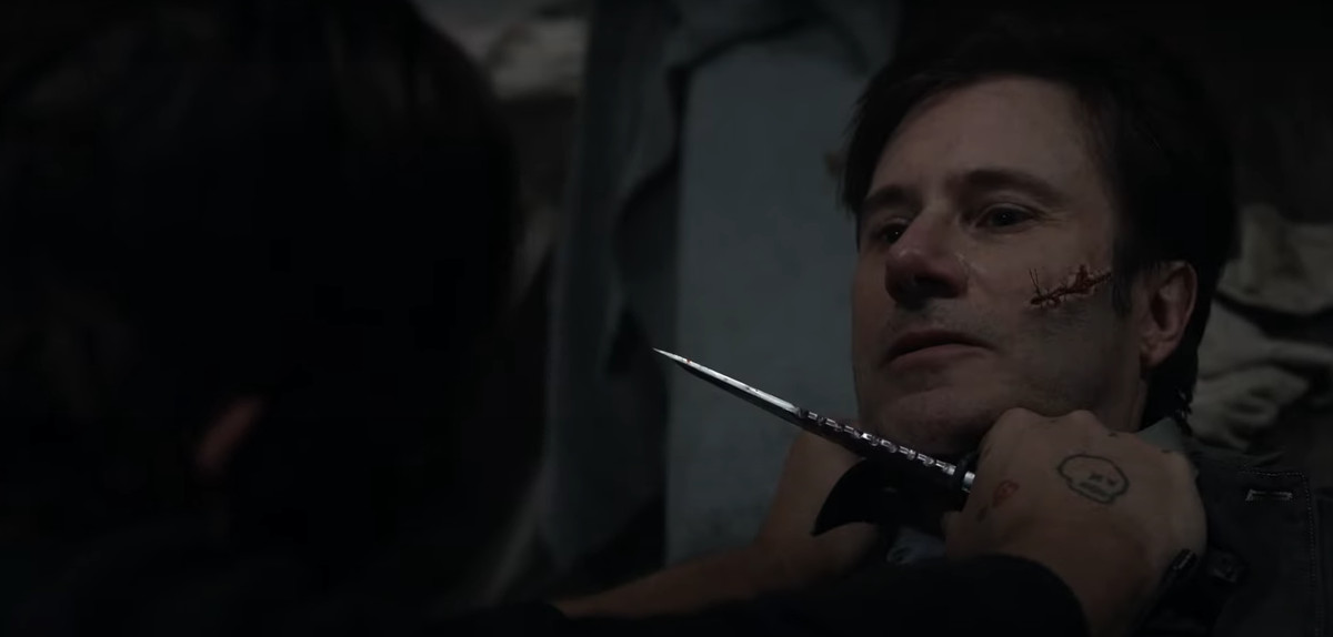Daryl di The Walking Dead punta un coltello alla gola di un uomo con un grosso taglio sulla guancia che è stato cucito.
