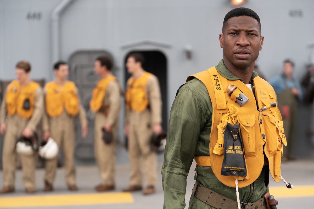 Jesse Brown (Jonathan Majors) si trova sul ponte di una nave con l'equipaggiamento da pilota da caccia della Marina e un giubbotto di salvataggio gonfiabile in Devotion
