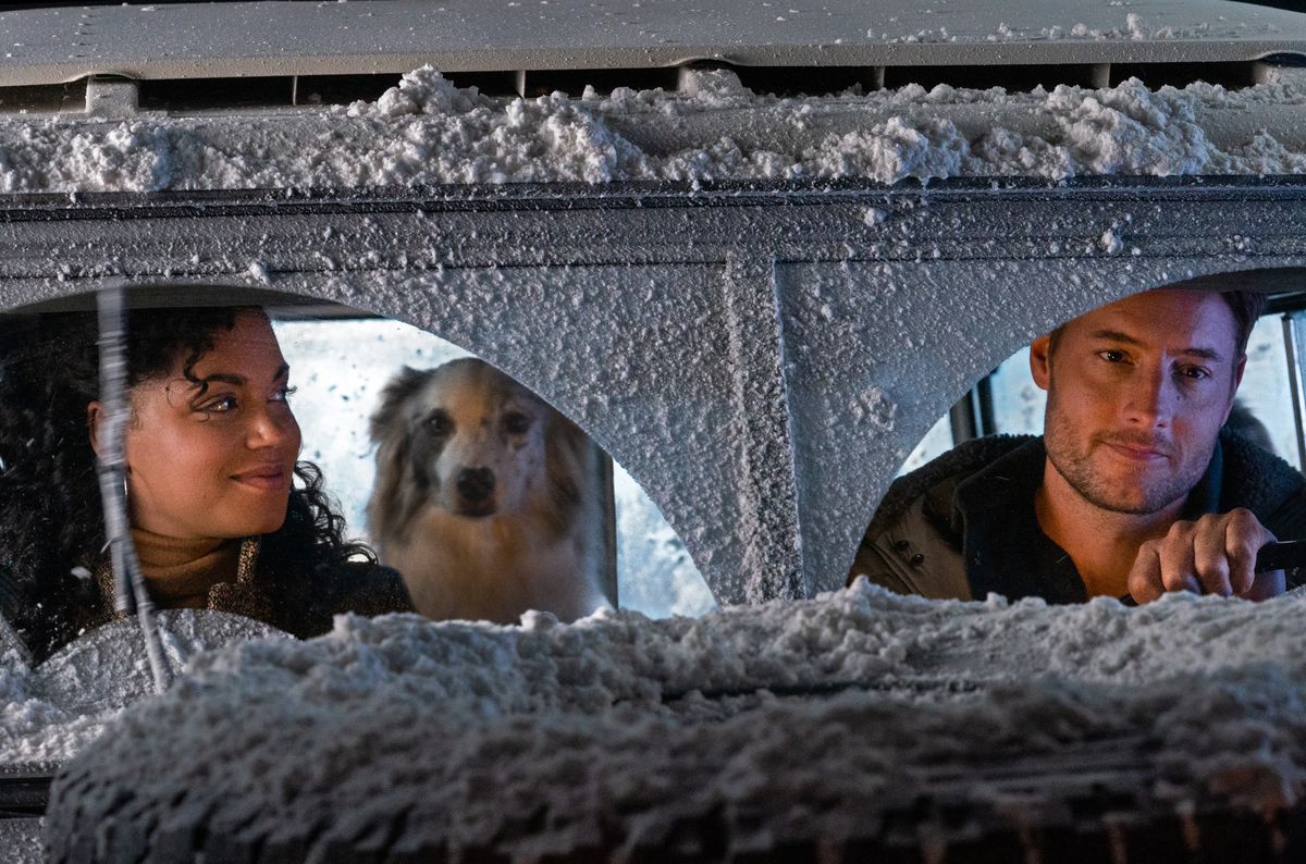 Una donna (Barrett Doss) sorride a un uomo (Justin Hartley) alla guida di un'auto coperta di neve con un cane sul sedile posteriore.